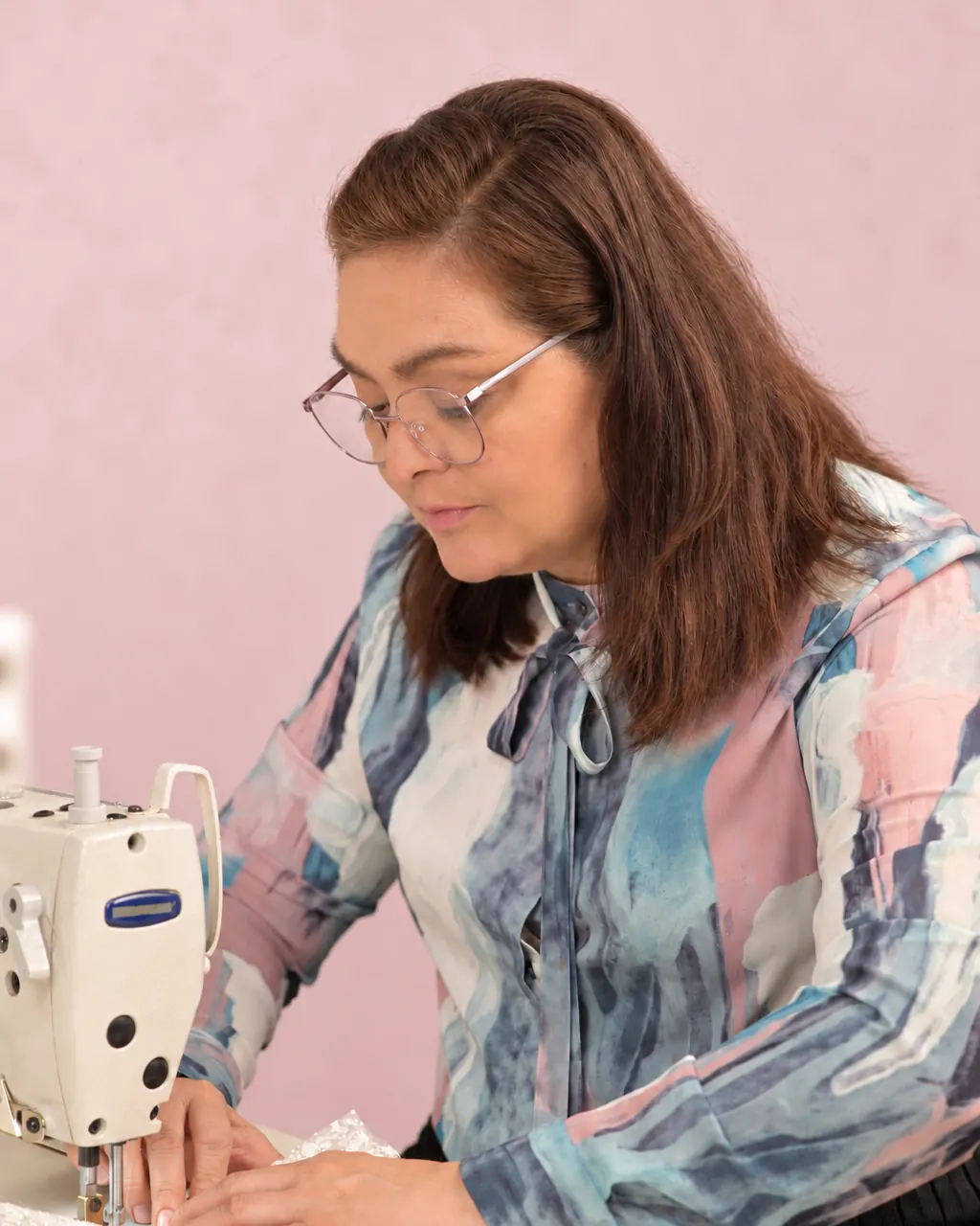 Kita Restrepo cose un encaje en la máquina del atelier